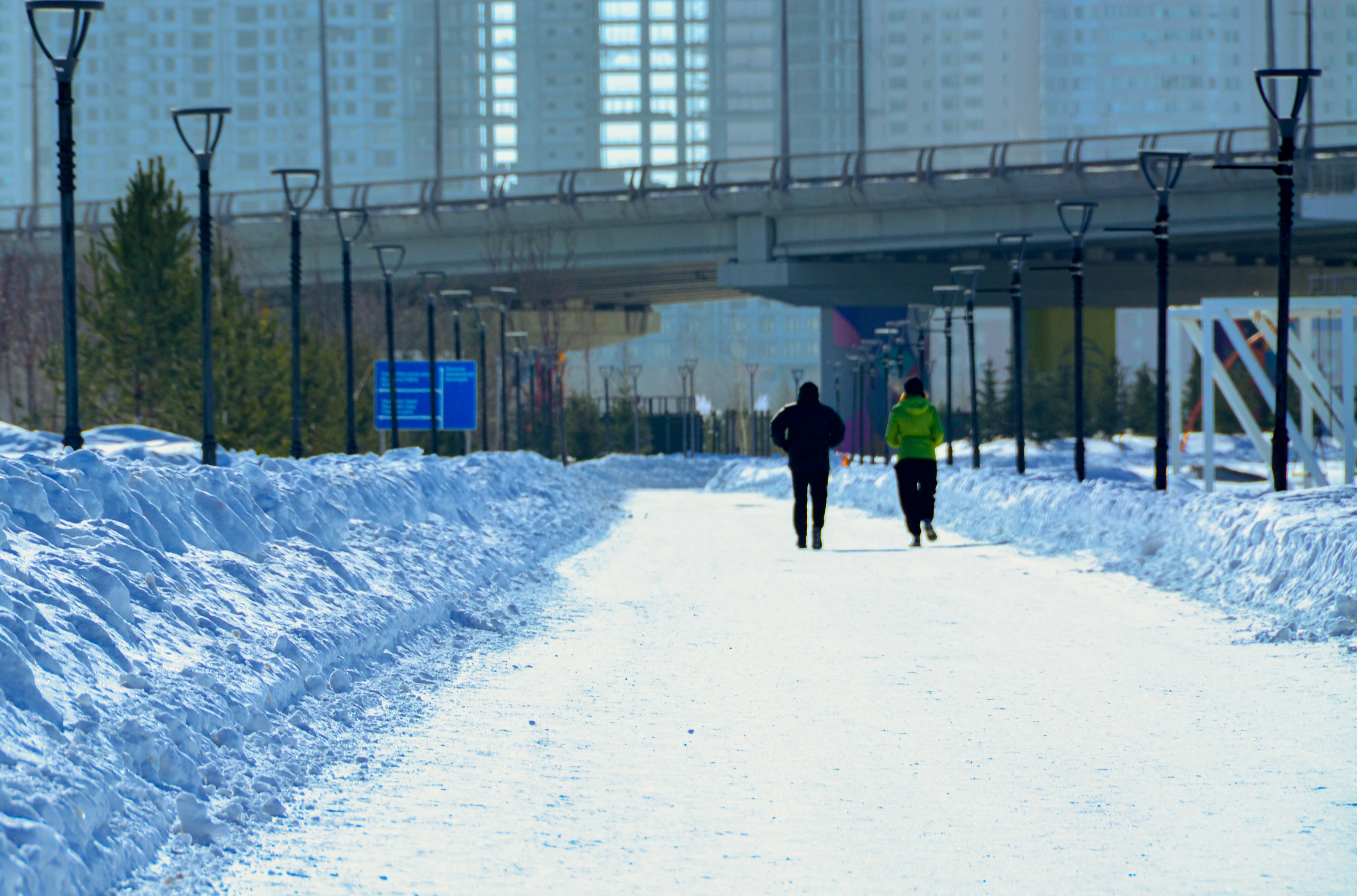 a couple of people walking down a snow covered road