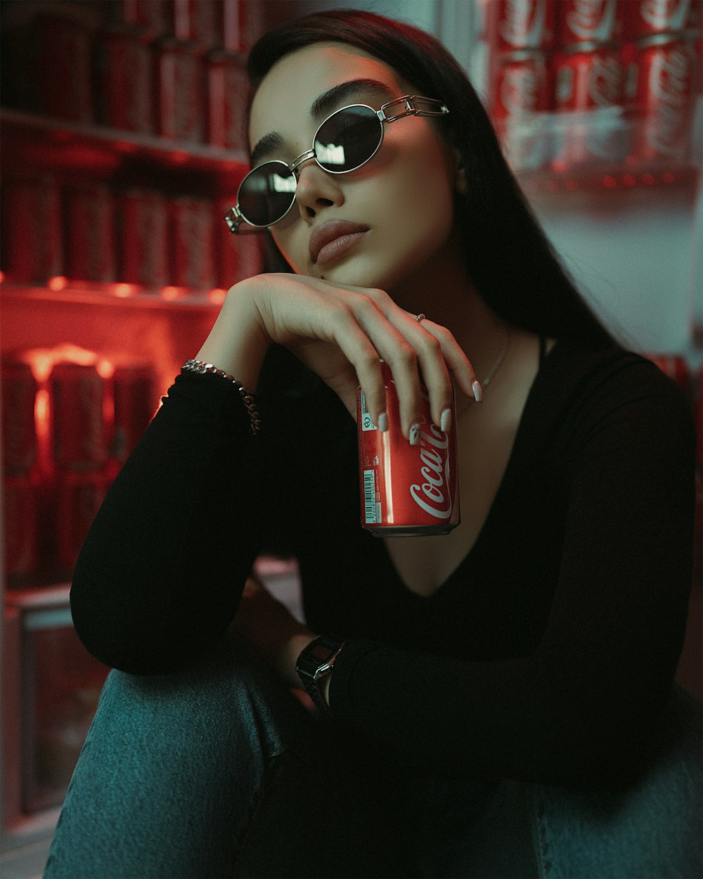 a woman wearing sunglasses and holding a can of coca cola