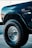 a blue truck with big tires parked in a parking lot