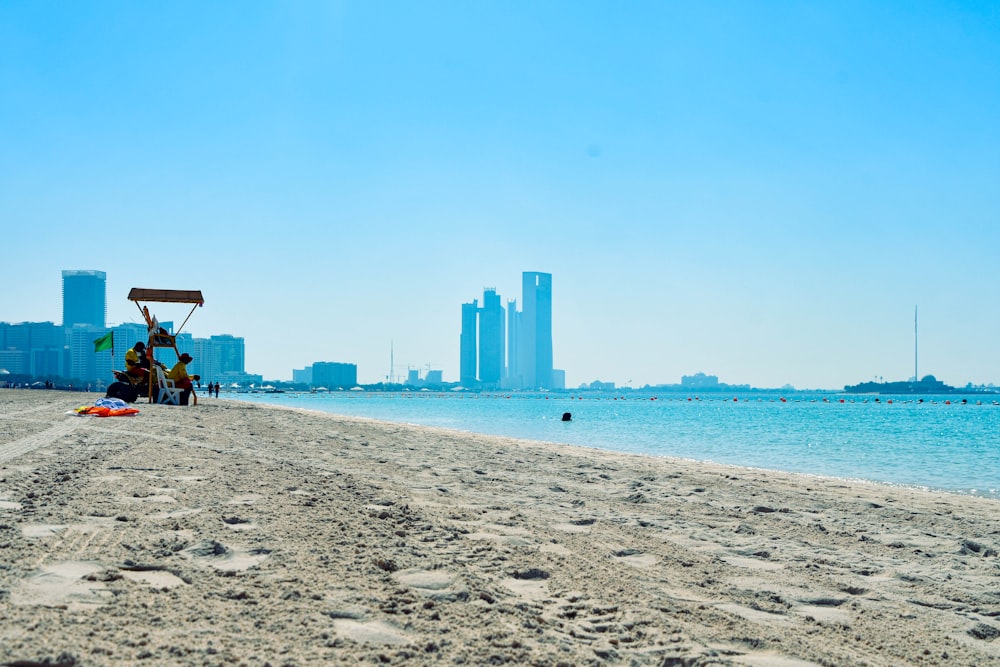 a couple of people sitting on top of a sandy beach