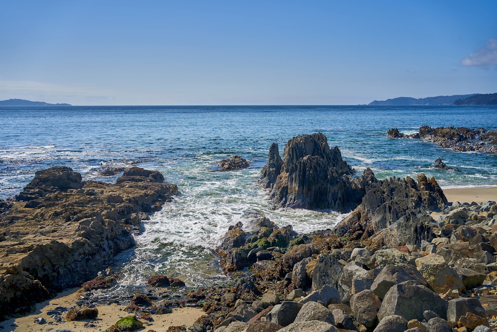 a rocky beach with a body of water in the background