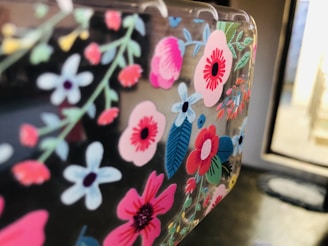 A close-up view of a surface decorated with vibrant, colorful floral patterns featuring flowers in shades of pink, red, blue, and white, with green leaves.