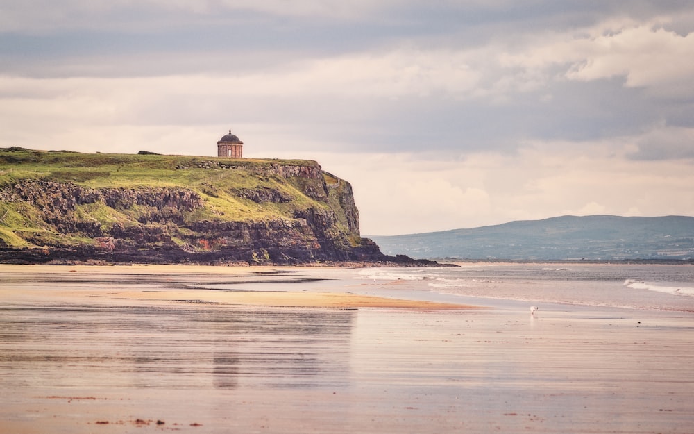 a small tower on top of a hill next to the ocean