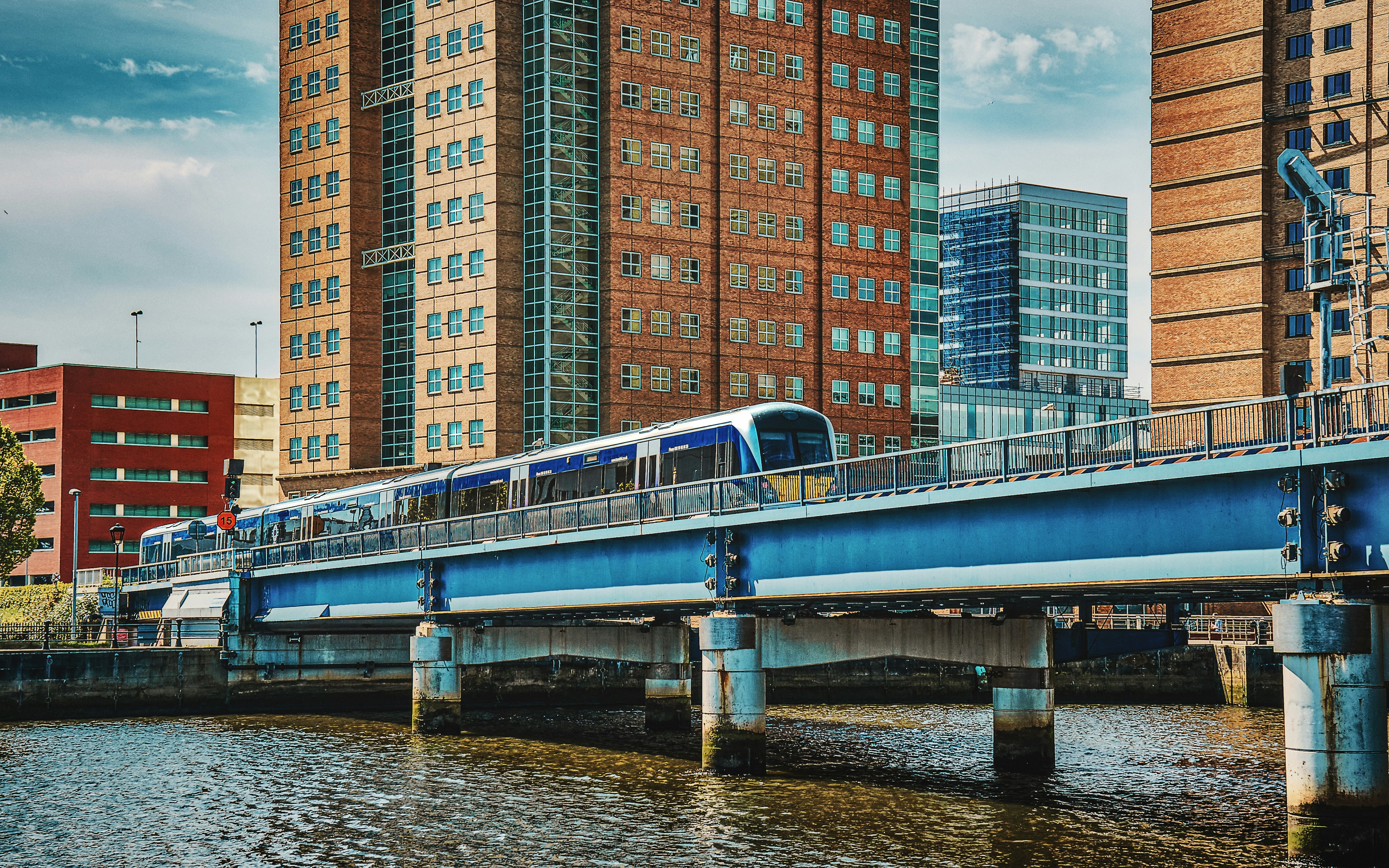 a blue and white train traveling over a bridge, A commuter train traveling over the River Lagan at Belfast Waterfront (May, 2019).