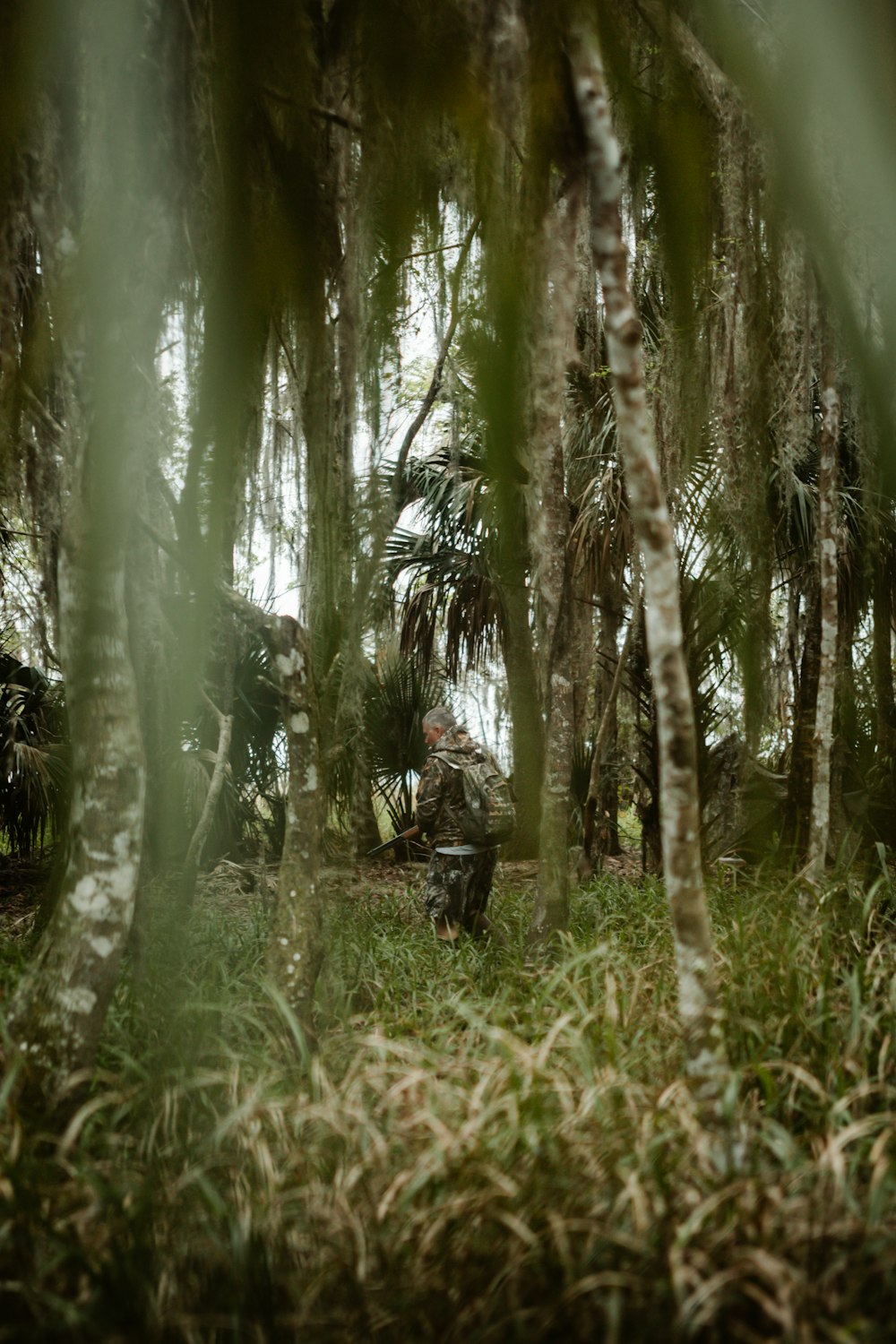 a man in camouflage sitting in the middle of a forest