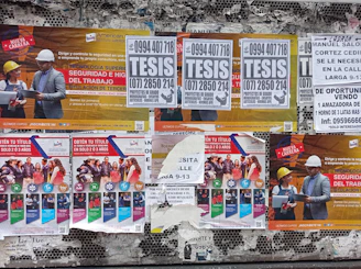 a bunch of posters on the side of a building