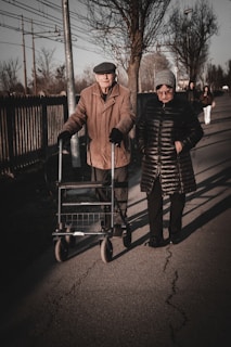 an older couple walking down the street with a walker