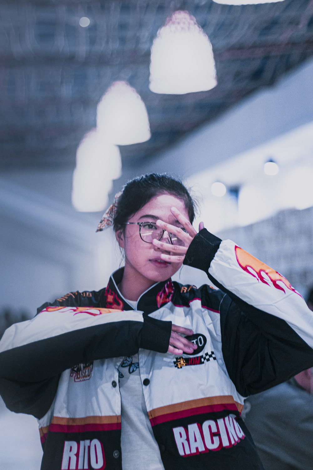 a woman in a racing jacket is covering her eyes