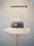 A beige wide-brimmed hat is displayed on a stand against a neutral background. Above the hat, the text 'HUTMANUFAKTUR SEIT 1903' is visible, suggesting a hat manufacturer established in 1903.