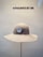 A beige wide-brimmed hat is displayed on a stand against a neutral background. Above the hat, the text 'HUTMANUFAKTUR SEIT 1903' is visible, suggesting a hat manufacturer established in 1903.