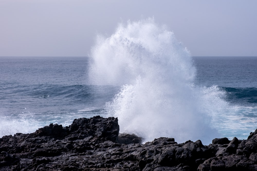 a large wave hitting on the rocks near the ocean