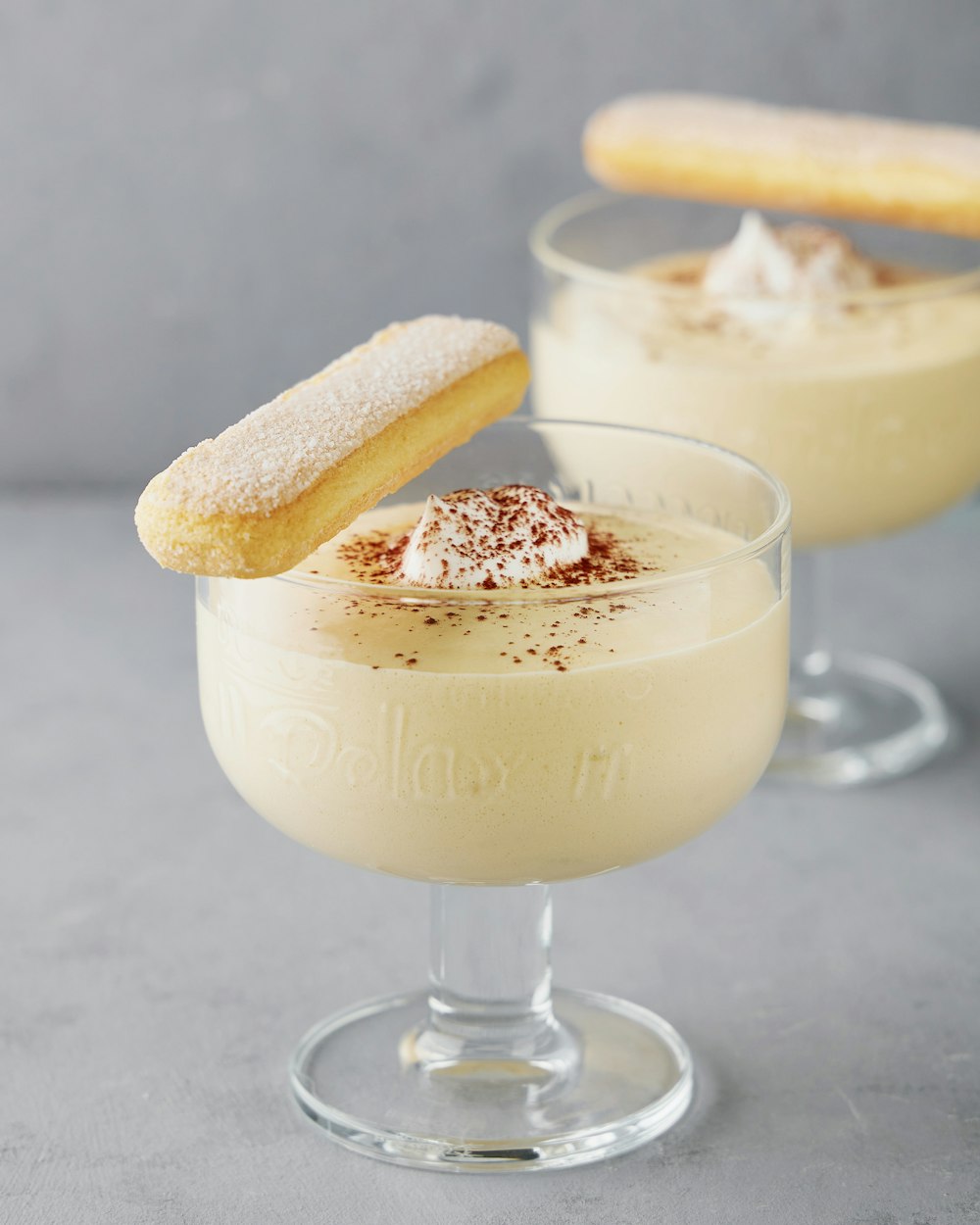 two desserts in glasses with a cookie on top