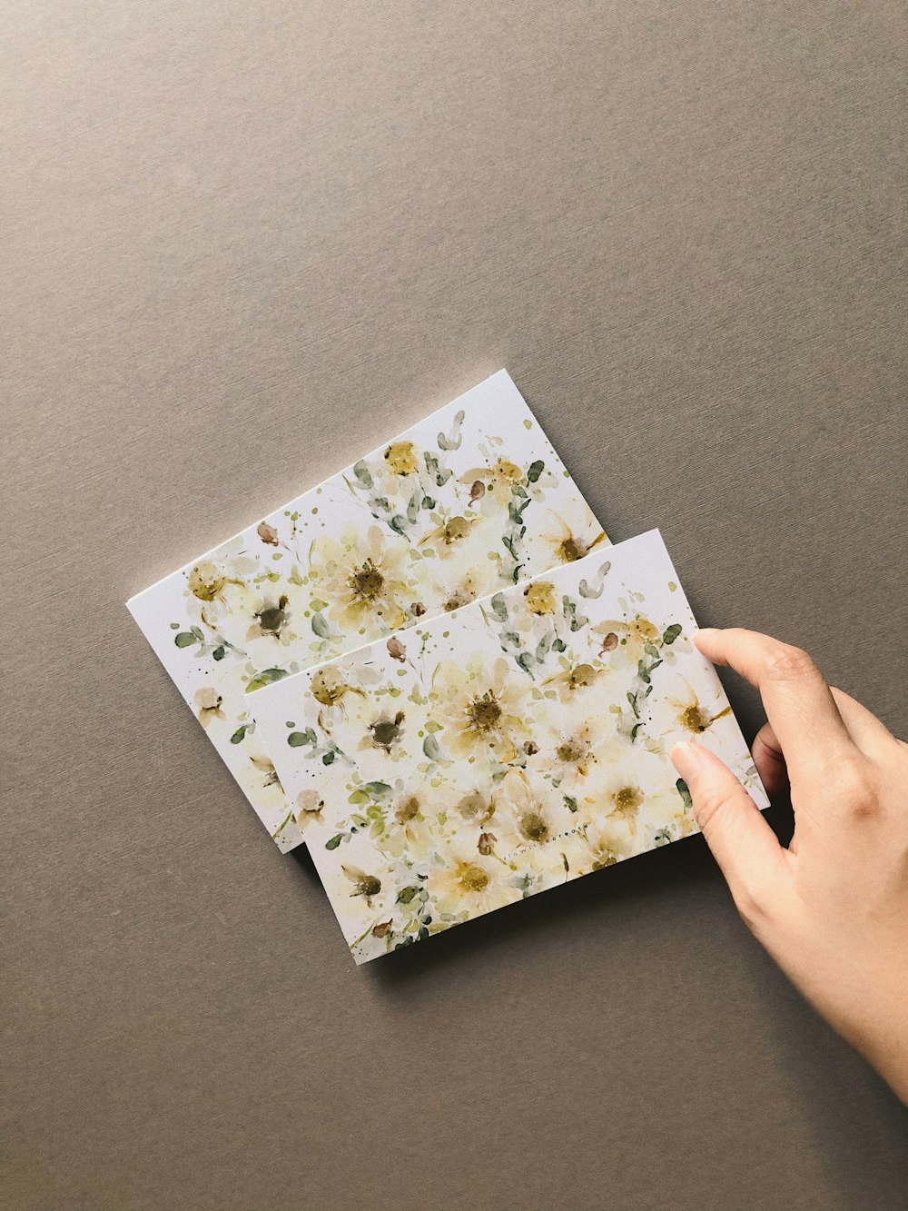 a person is holding a piece of paper with flowers on it