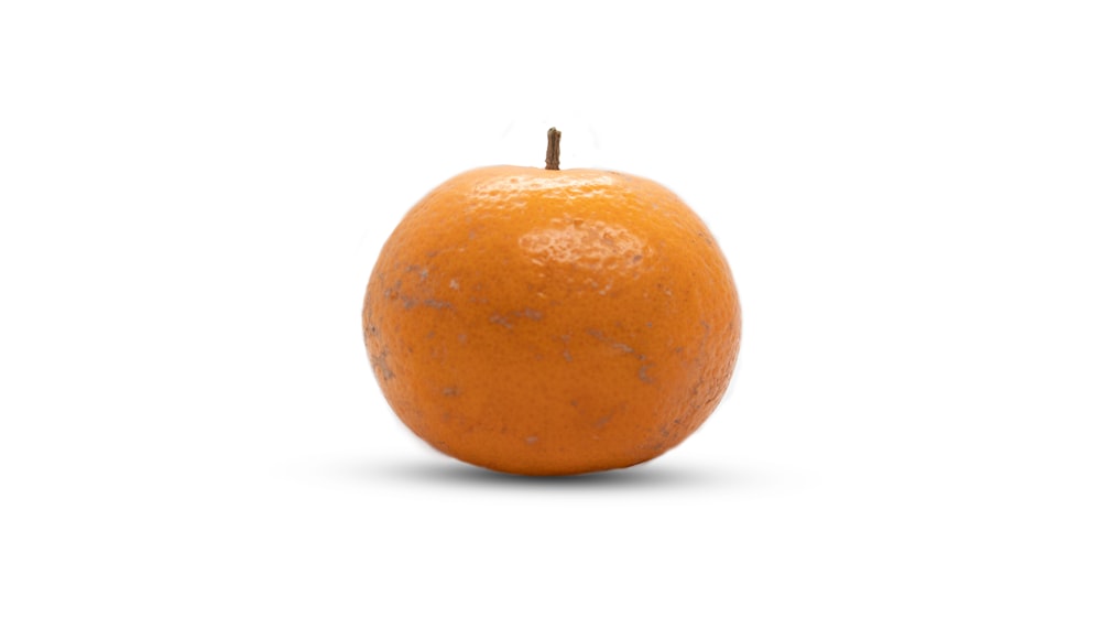 a single orange sitting on top of a white surface