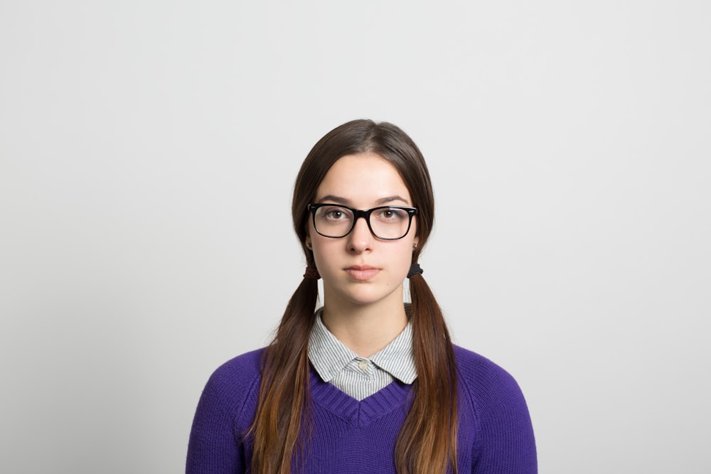 uma mulher que usa óculos e um suéter roxo