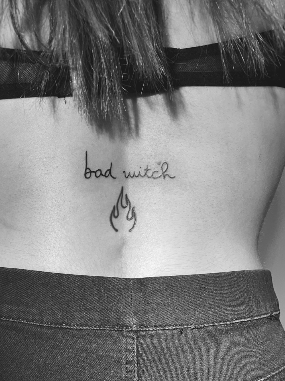 a woman's lower back with a tattoo saying bad witch