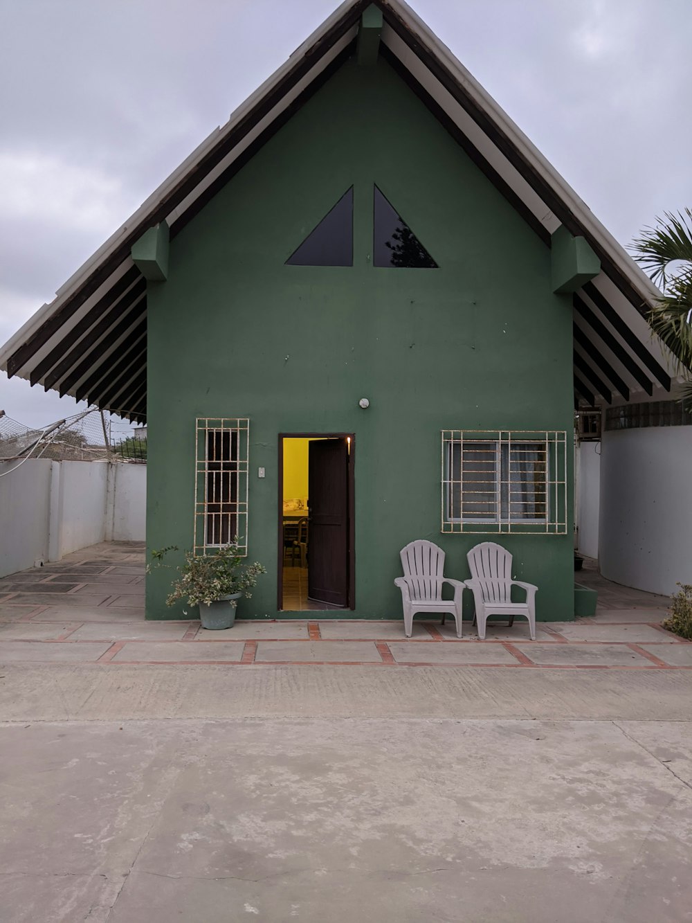 a green house with two chairs in front of it