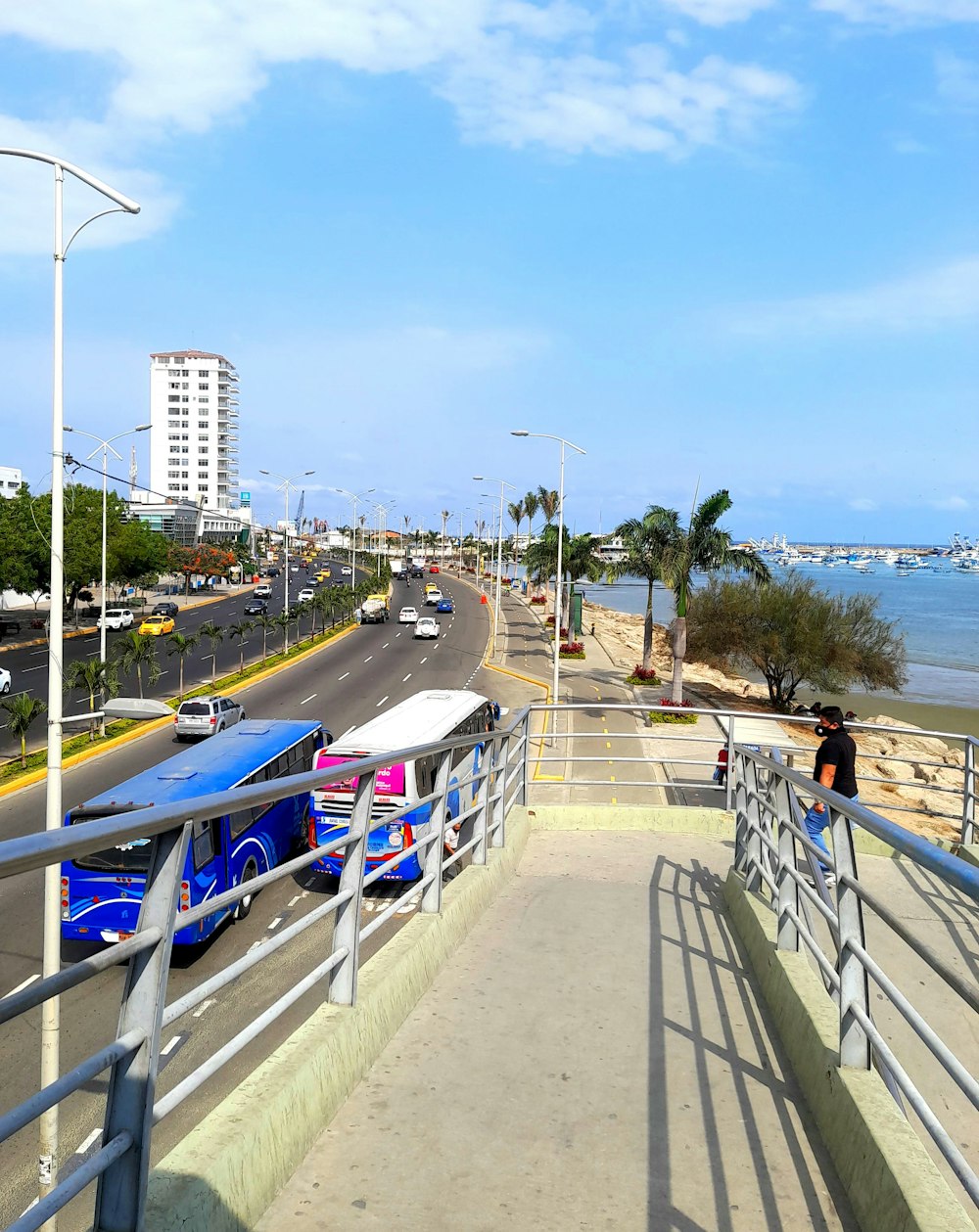 a blue and white bus driving down a street next to the ocean