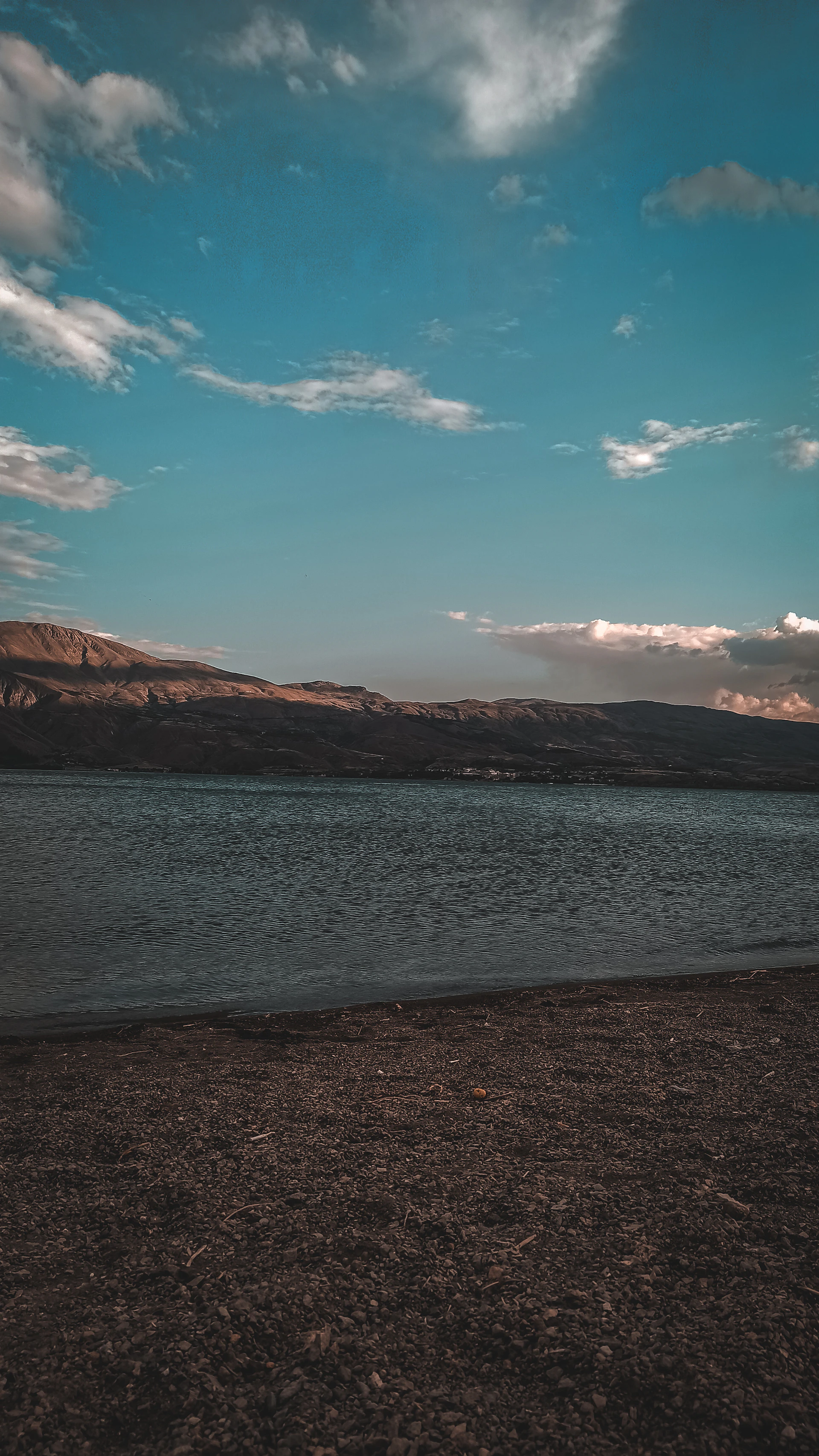 a large body of water sitting under a cloudy blue sky
