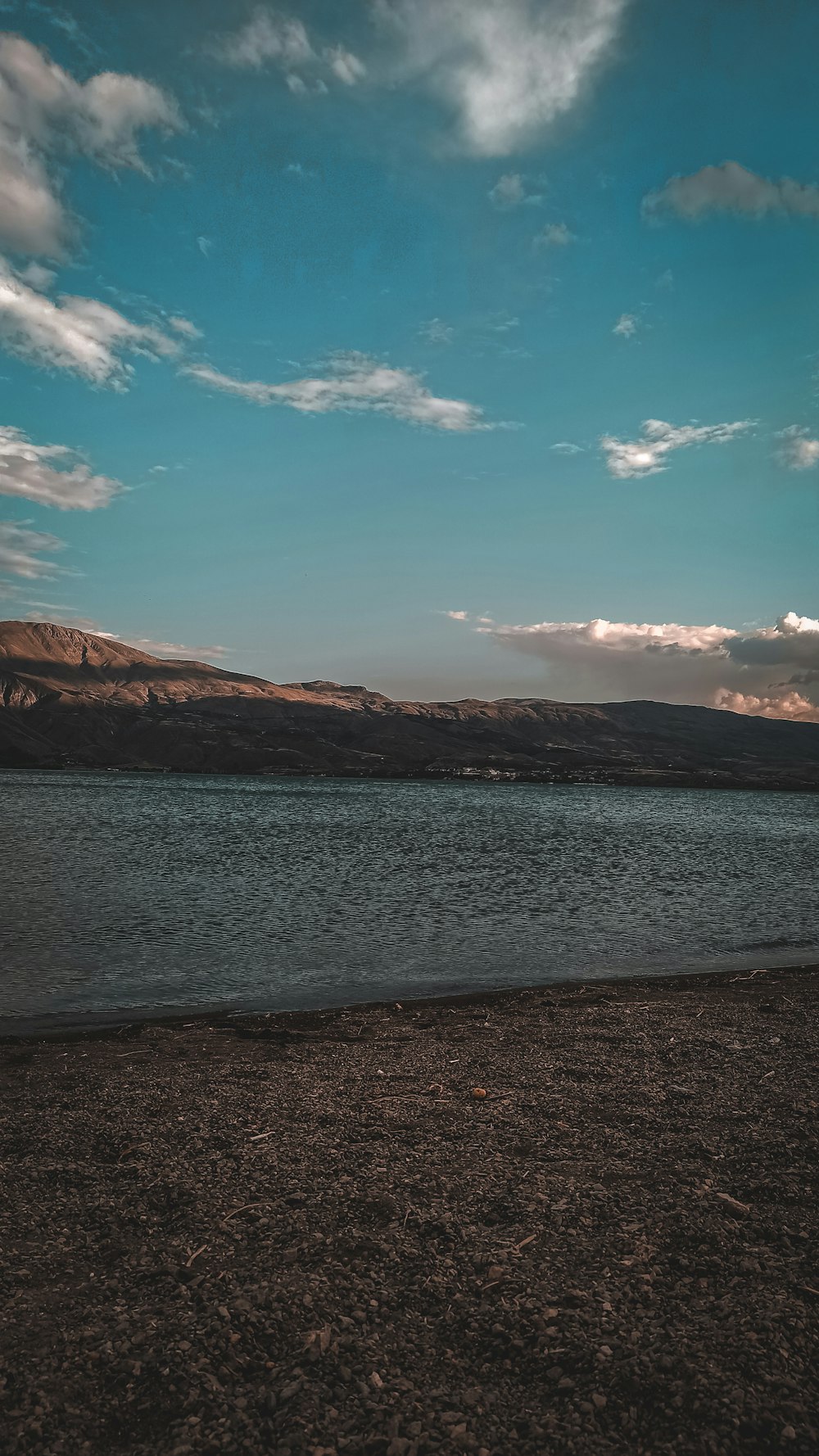 a large body of water sitting under a cloudy blue sky