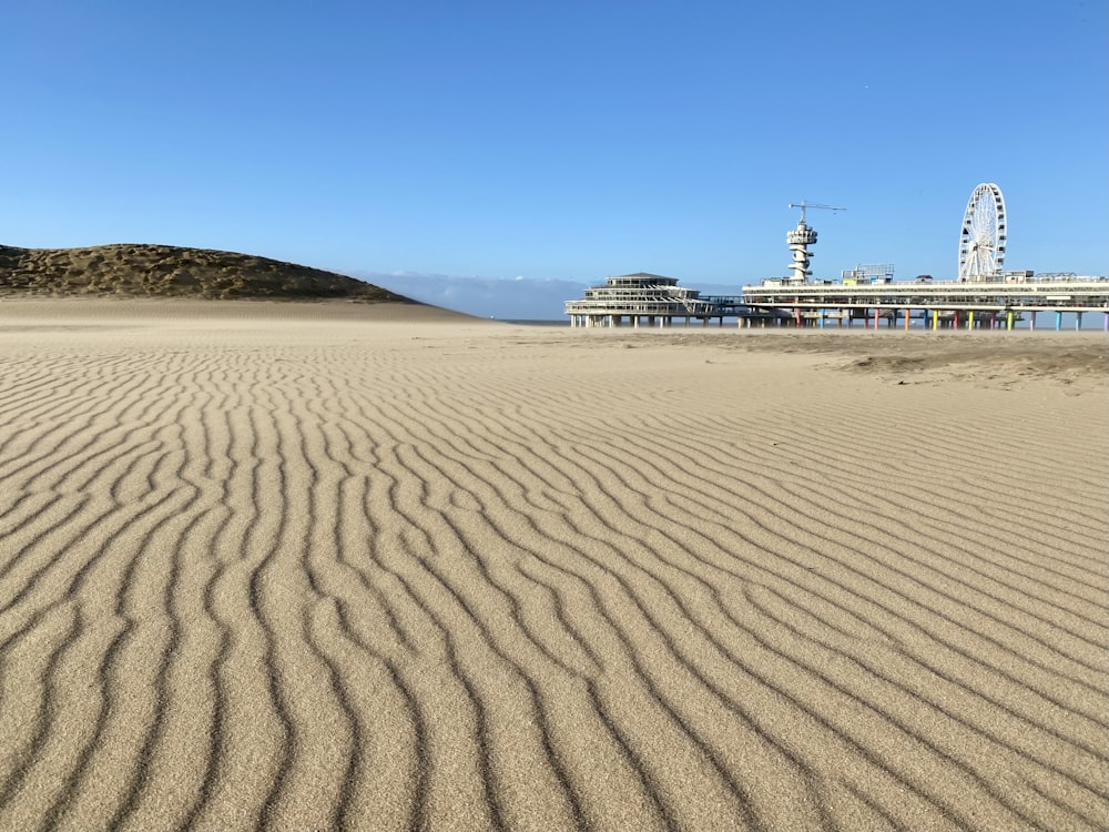 a sandy beach with a ferris wheel in the background