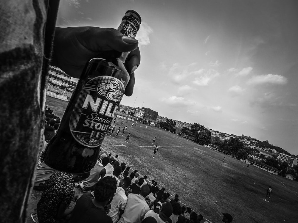 a person holding a bottle of beer in front of a crowd
