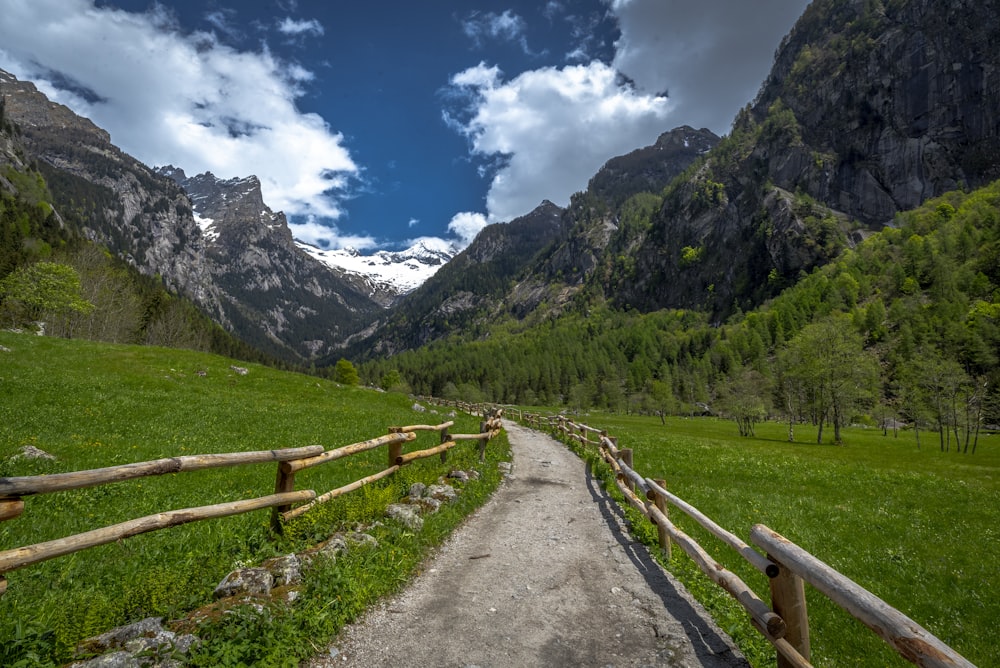 a wooden fence in a grassy field with mountains in the background