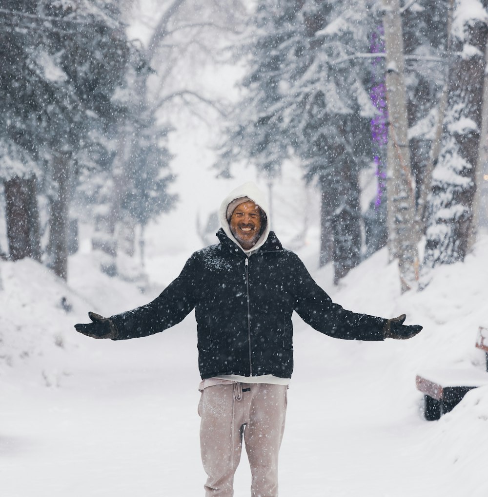 a man standing in the snow with his arms outstretched