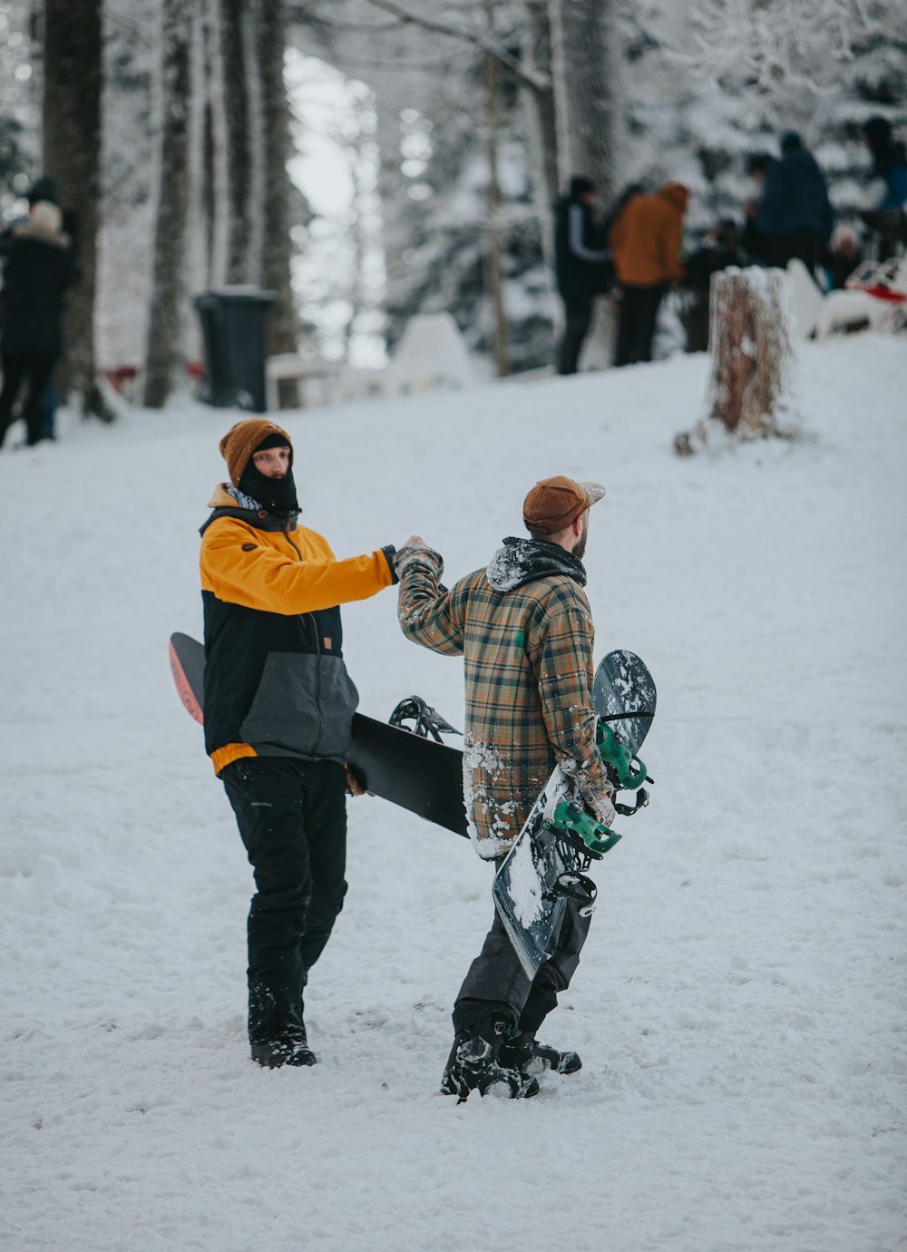 two people standing in the snow with snowboards