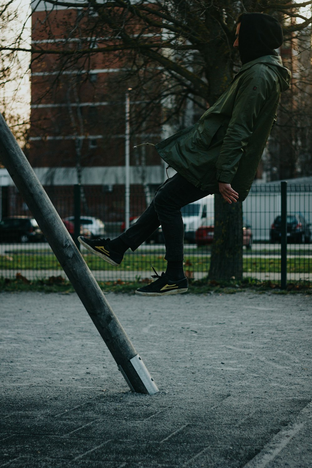 a man in a green jacket is playing on a metal pole