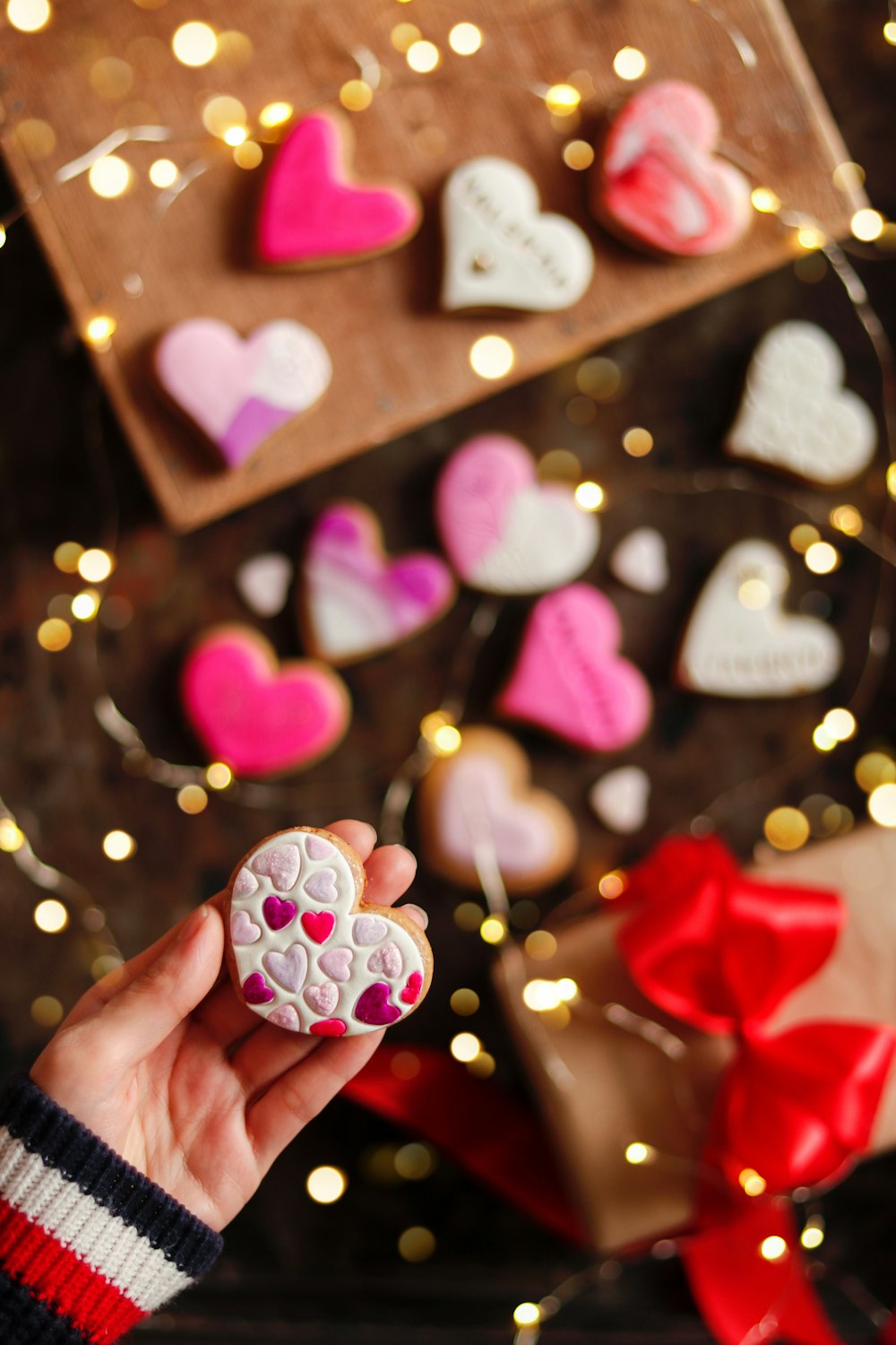 a person holding a heart shaped cookie in their hand