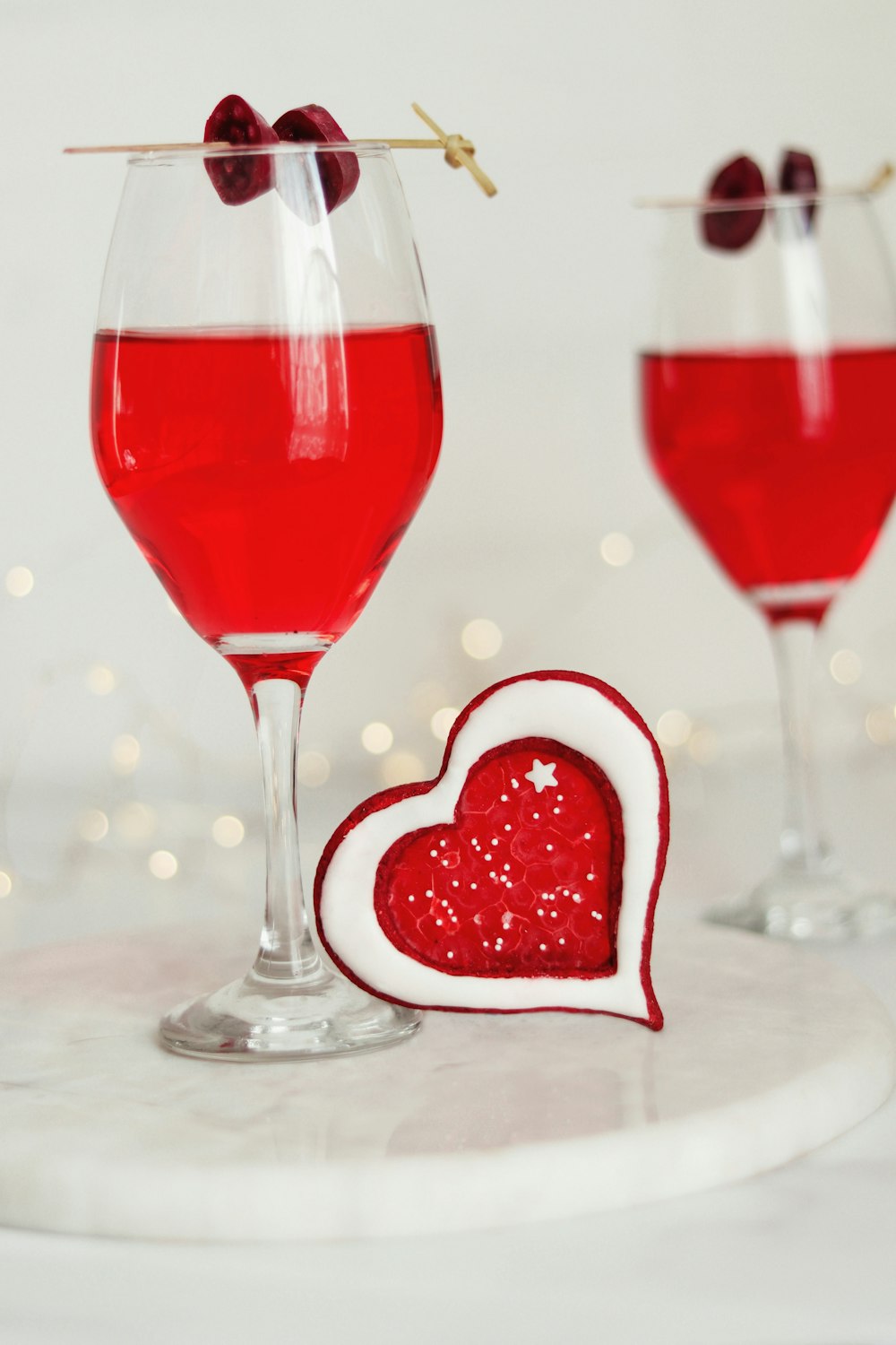 two glasses of red wine with a heart shaped decoration