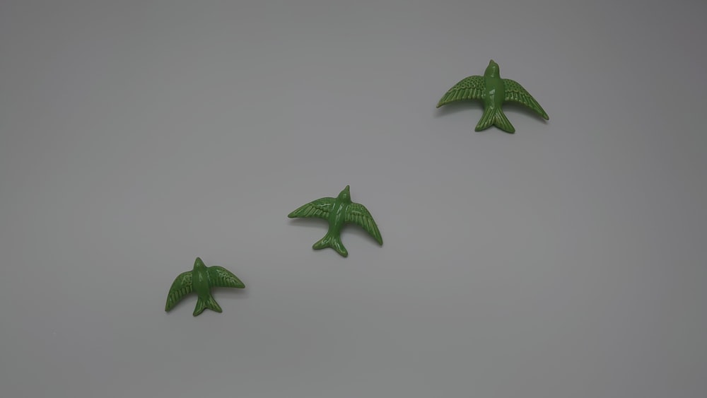 three green plastic birds flying in the air