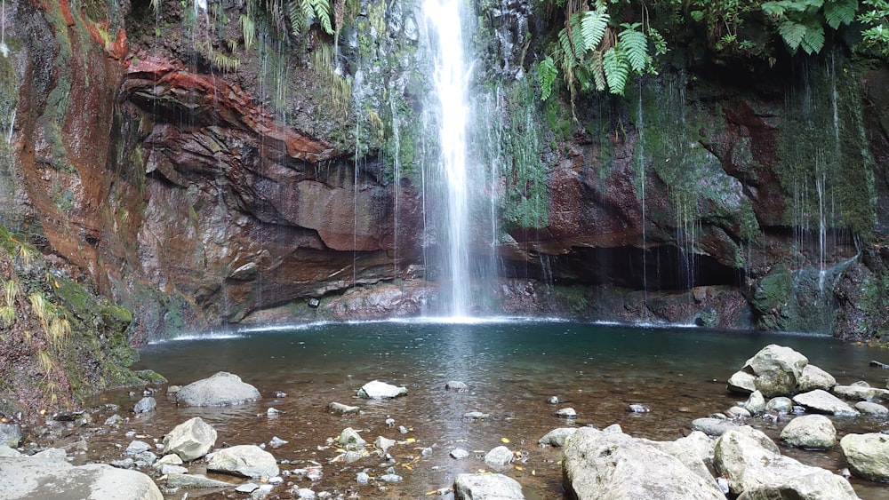 a large waterfall is in the middle of a rocky area