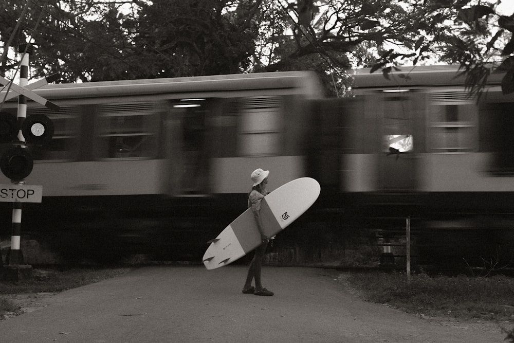 a man holding a surfboard walking down a street