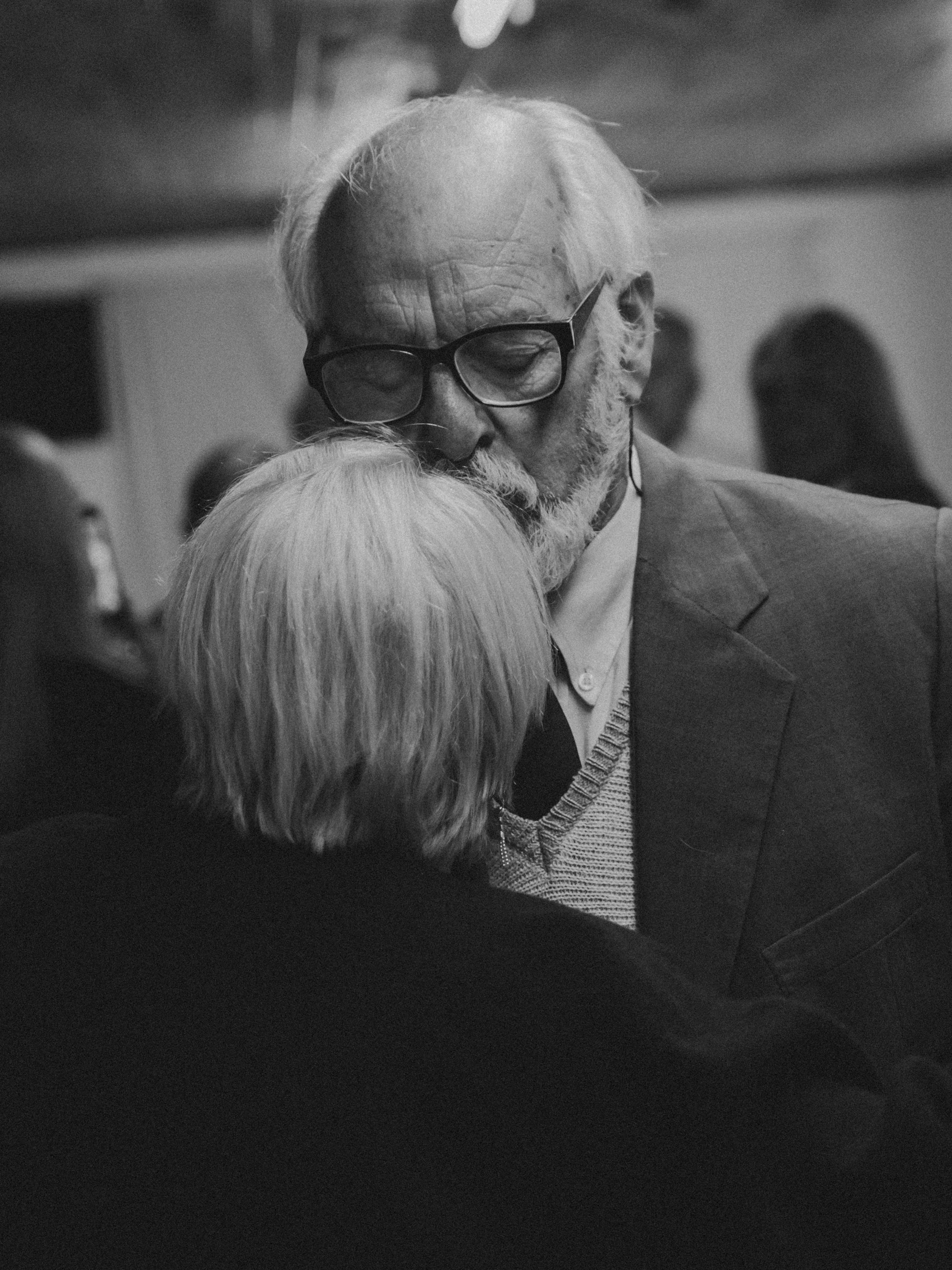 Foto de una pareja anciana en la que el hombre besa la frente de la mujer.