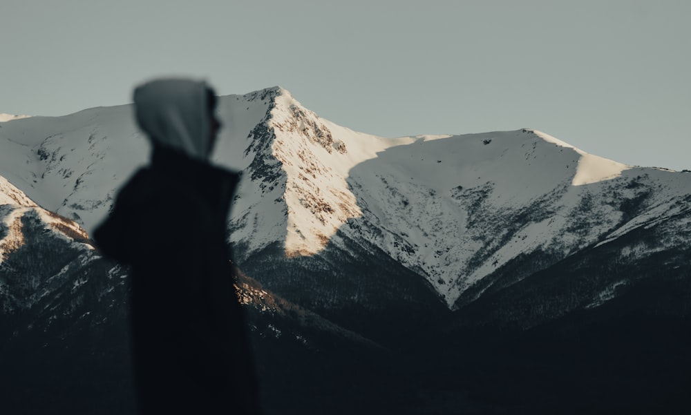 a person standing in front of a snow covered mountain