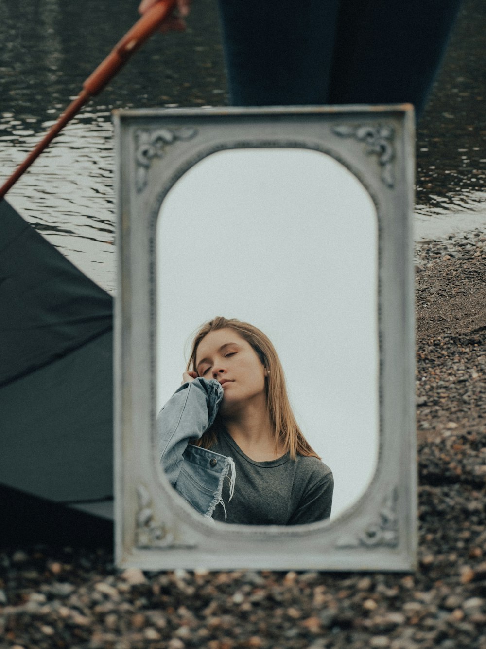 a woman standing in front of a mirror next to a body of water