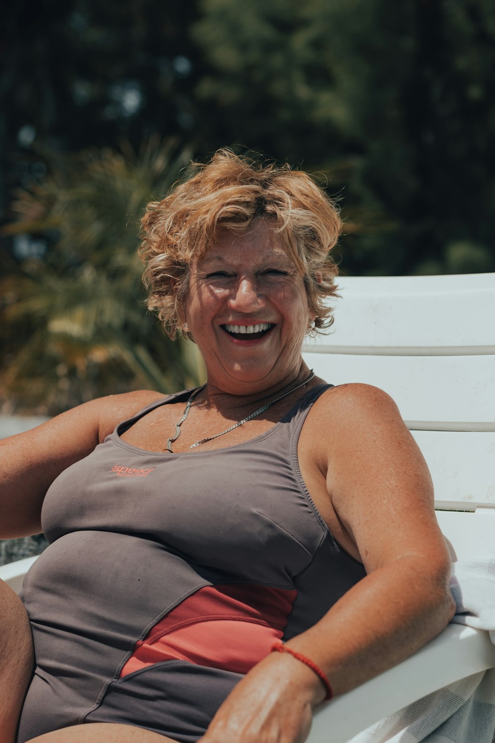 Una mujer sentada en un banco blanco sonriendo