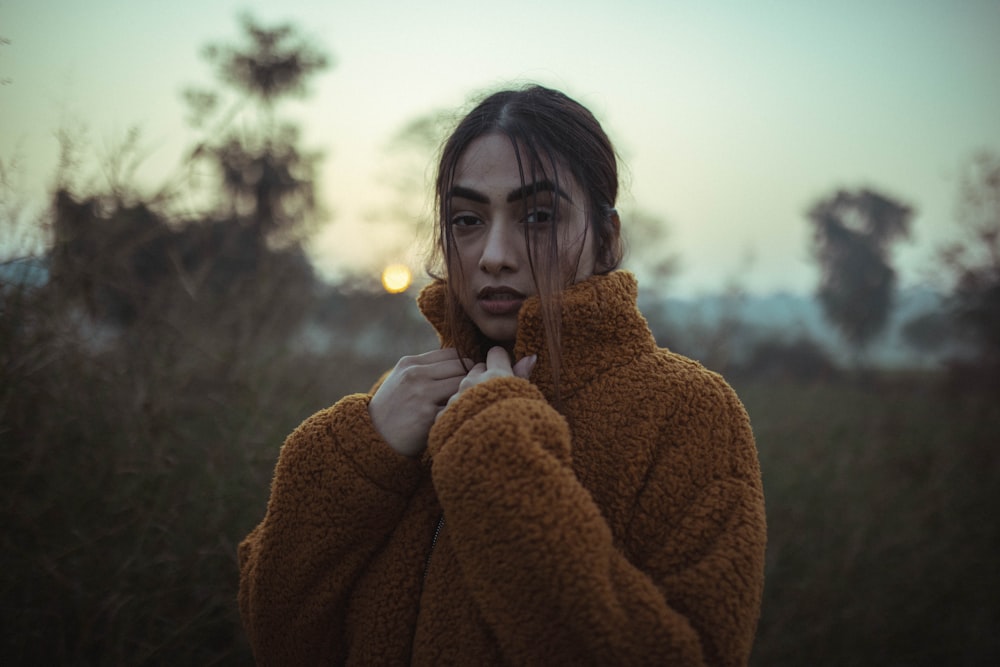 a woman standing in a field with her hands on her face