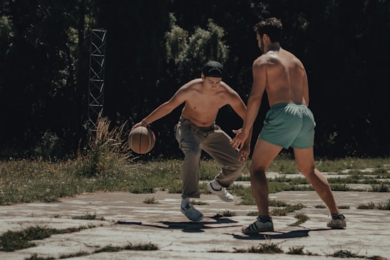 Players in action during an outdoor basketball pickup game under bright spring sunlight.