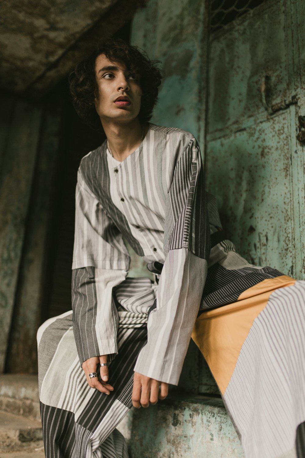 a young man sitting on top of a wooden bench