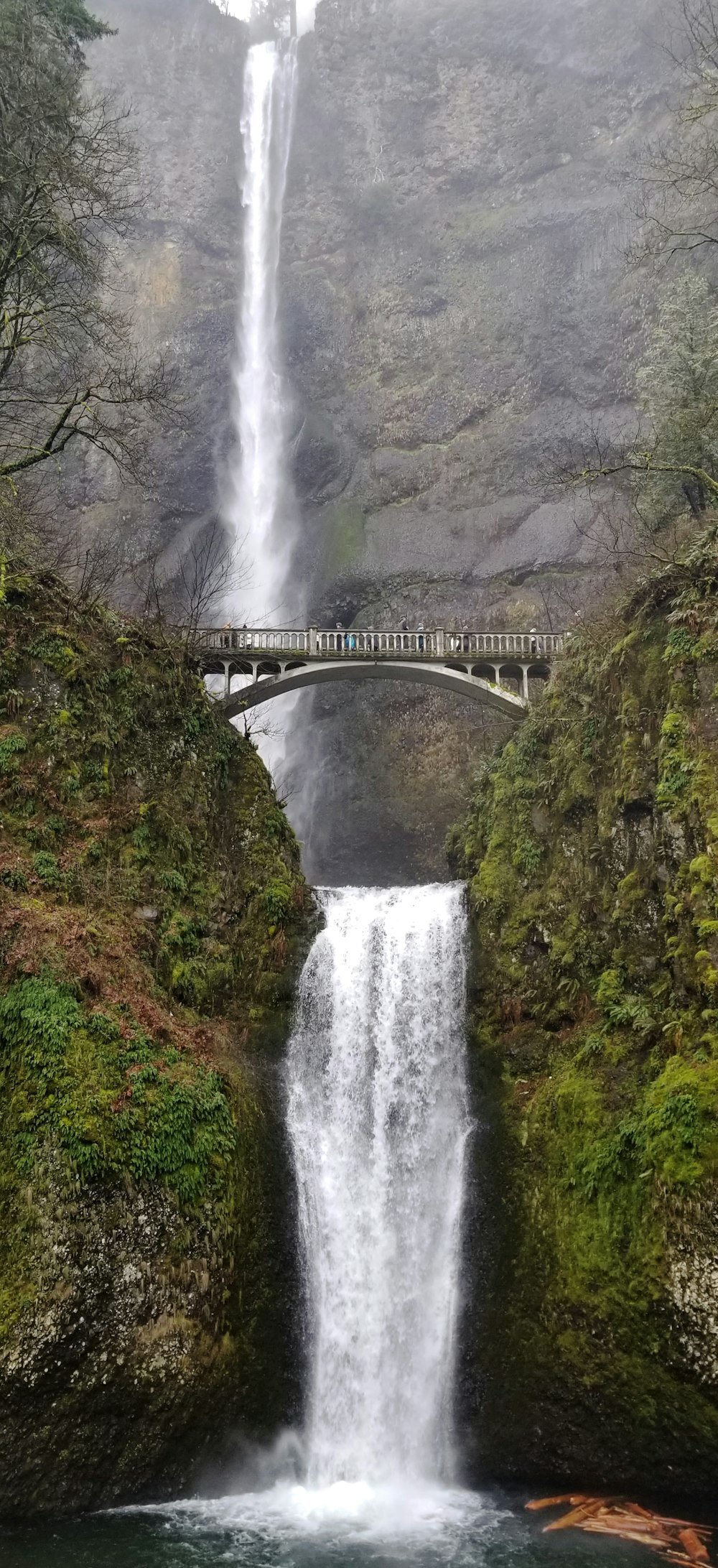 a large waterfall with a bridge over it