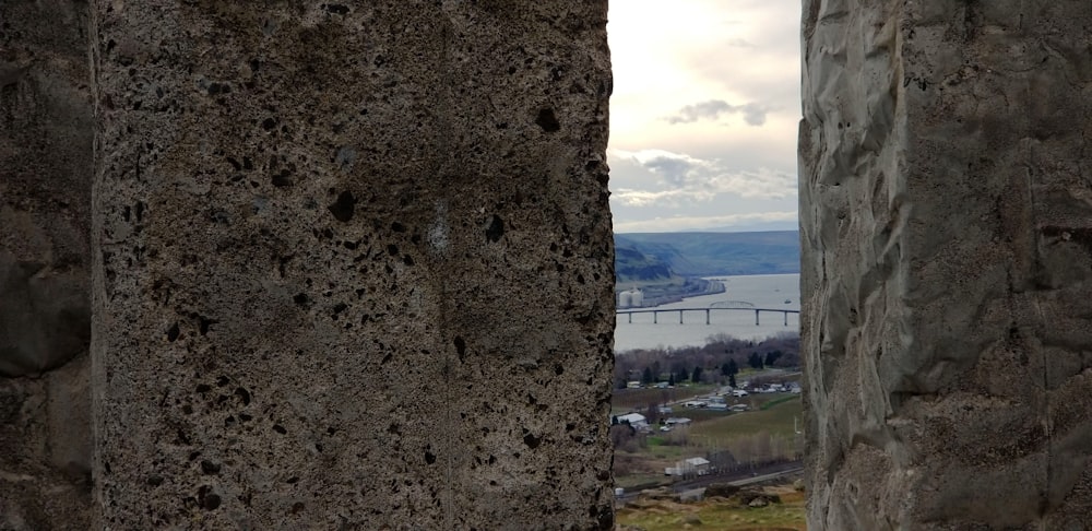 a stone wall with a view of a bridge in the distance