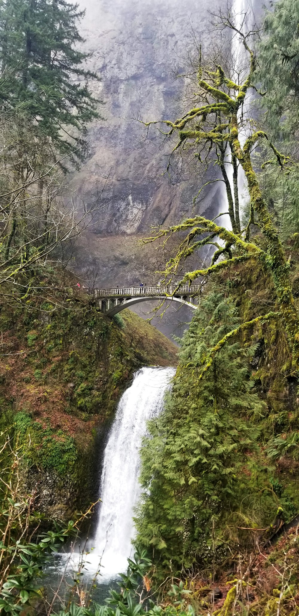 a waterfall with a bridge in the background