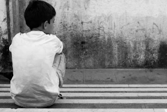 a young boy sitting on the side of a street
