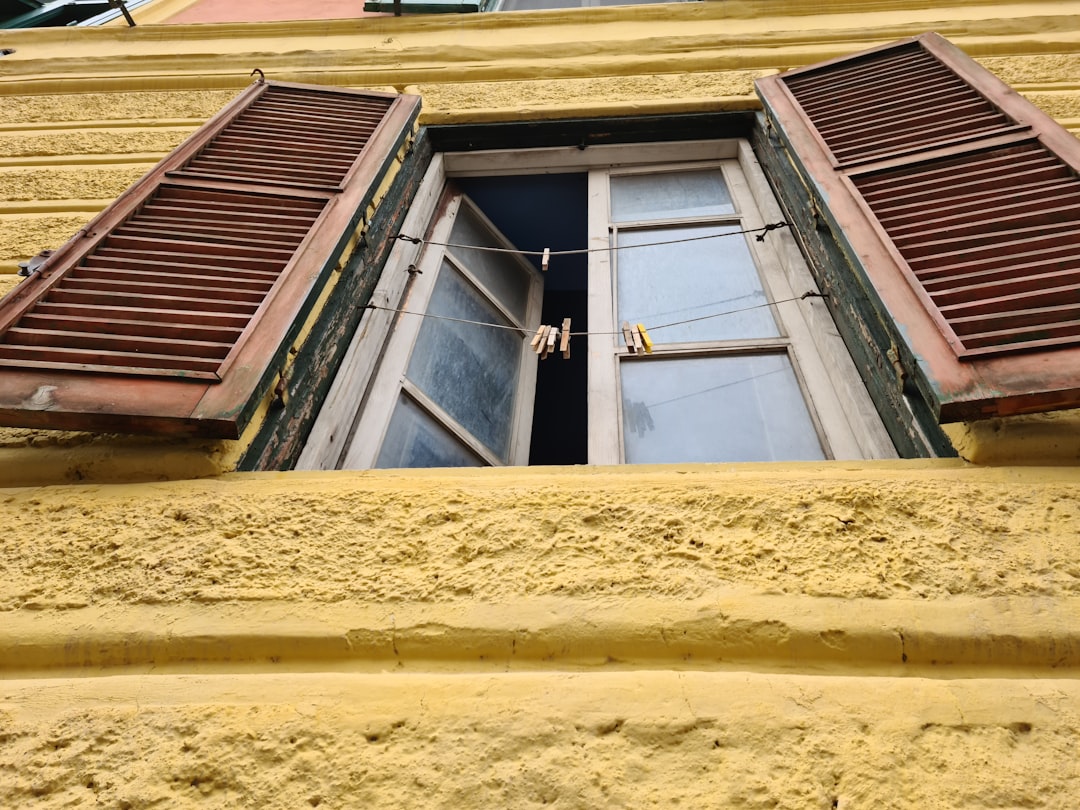 a yellow building with shutters open and clothes hanging on a line,