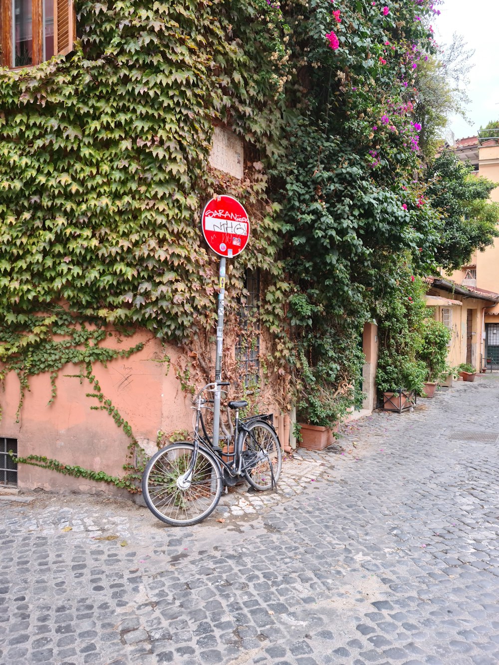 a bike parked next to a building covered in vines