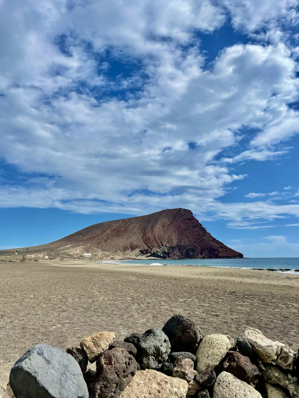 a beach with rocks and a mountain in the background