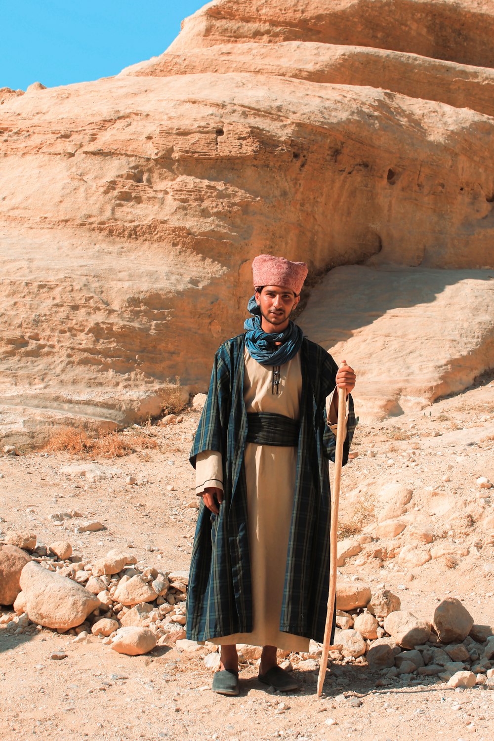 a woman standing in the desert holding a stick